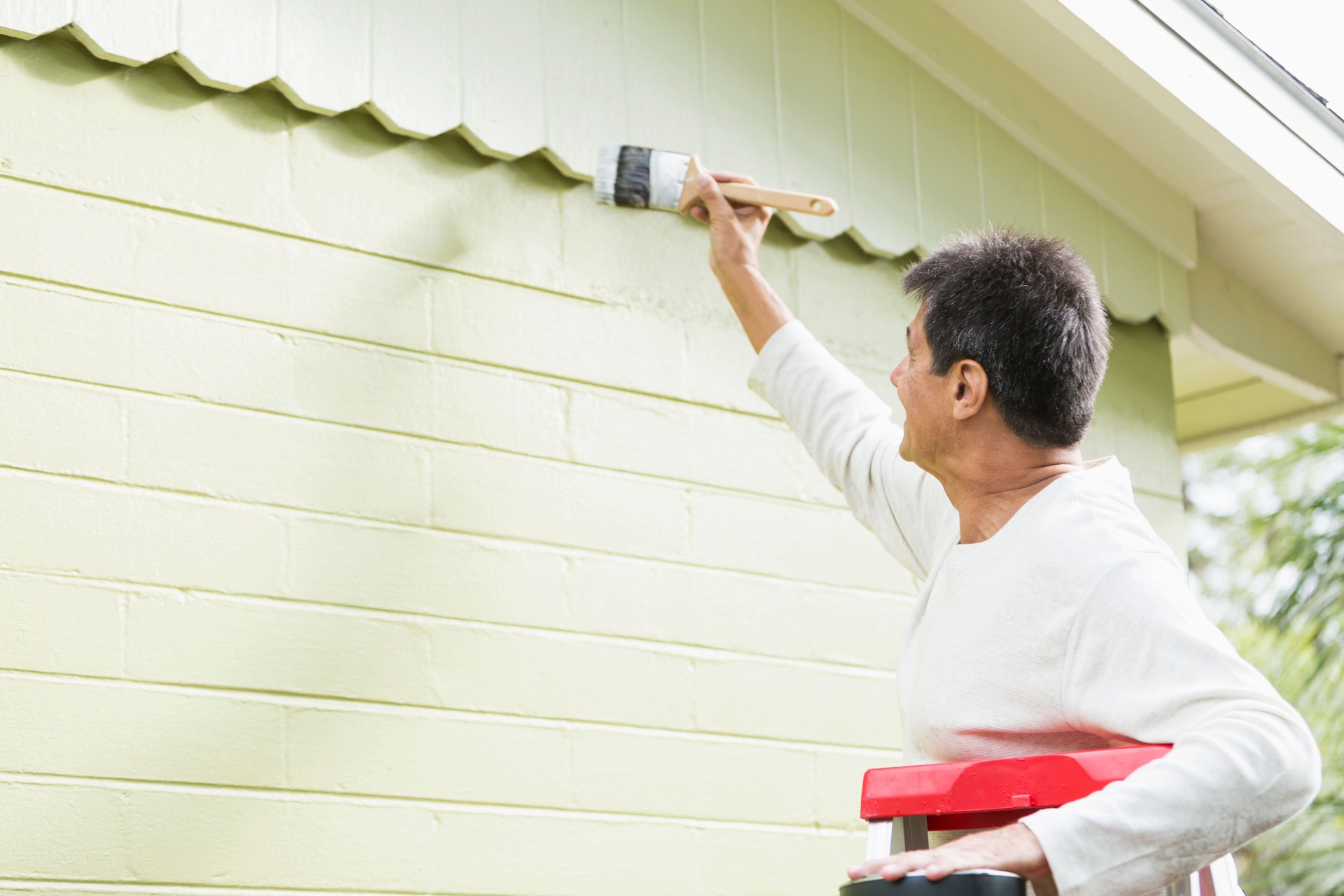 Hispanic man painting house