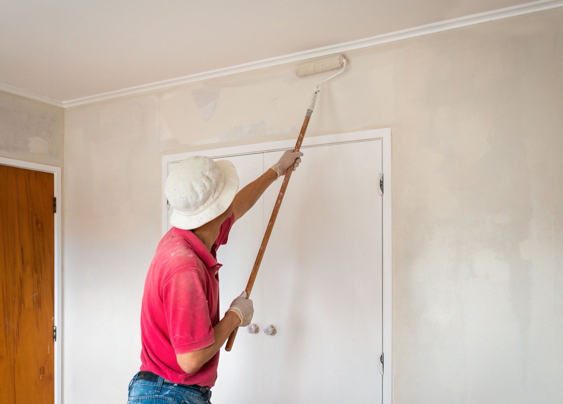 Man painting internal walls with a roller. Home renovation project. Auckland.